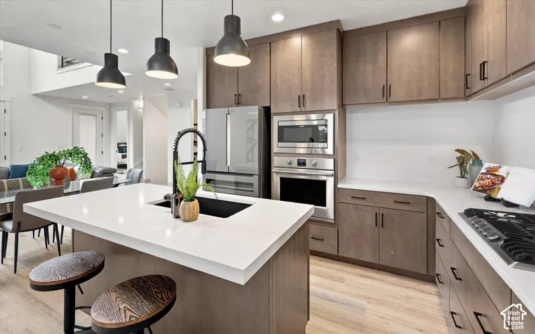 Contemporary kitchen featuring custom wood-finish cabinetry, white quartz countertops, and a waterfall-edge island