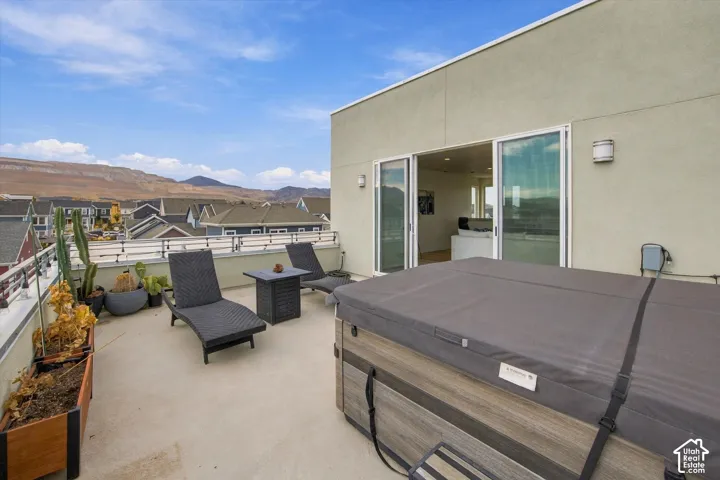 Rooftop deck featuring a spa, sliding glass doors, and a partial perimeter railing