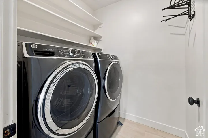 Integrated laundry area featuring built-in shelving, wood-finish flooring, and a wall-mounted drying rack