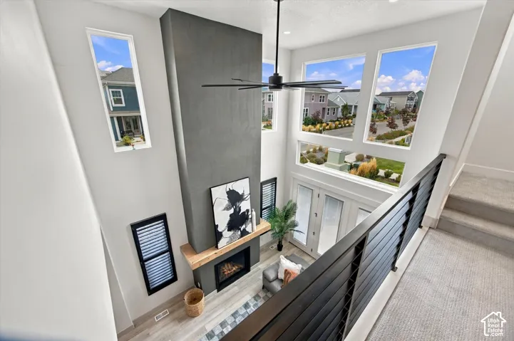 Modern loft-style landing featuring soaring ceilings, abundant natural light from multiple large windows, and a striking two-story fireplace with dark tile surround and wood mantel