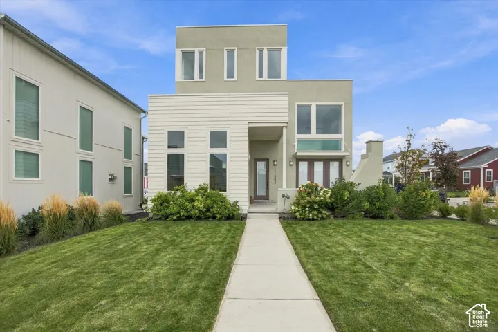 Modern architectural style with multiple large windows, stucco and horizontal siding facade, and a concrete walkway leading to the entrance