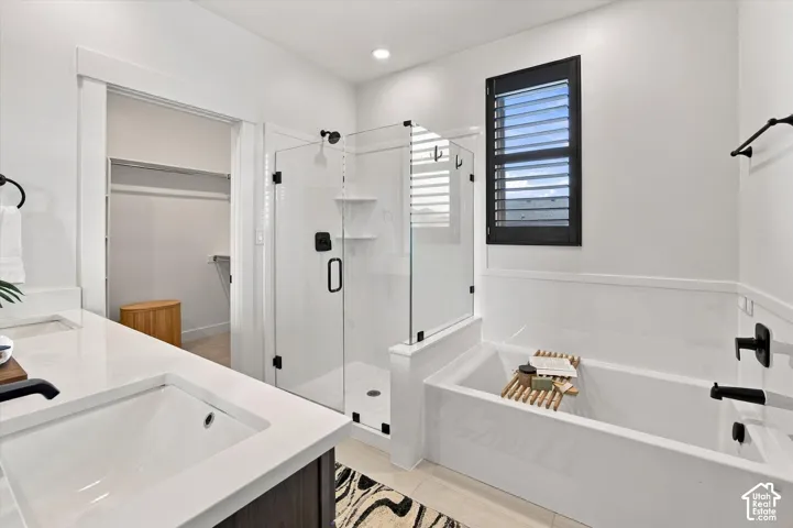 Built-in bathtub, glass-enclosed shower, white countertop with integrated sink, dark wood-finish vanity, and black window shutters