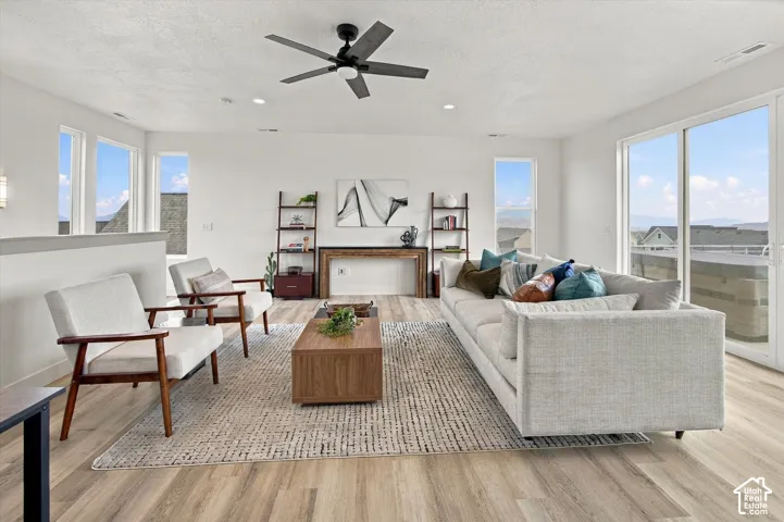 Light-filled living area featuring wood-finish flooring, a contemporary ceiling fan, and large sliding glass doors