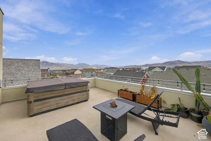 Rooftop deck featuring a built-in hot tub, concrete flooring, and metal railing