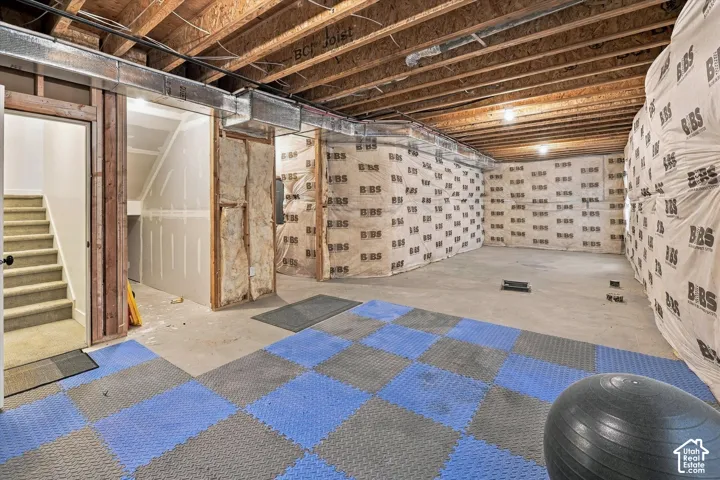 Unfinished basement space featuring exposed wood joists and concrete flooring