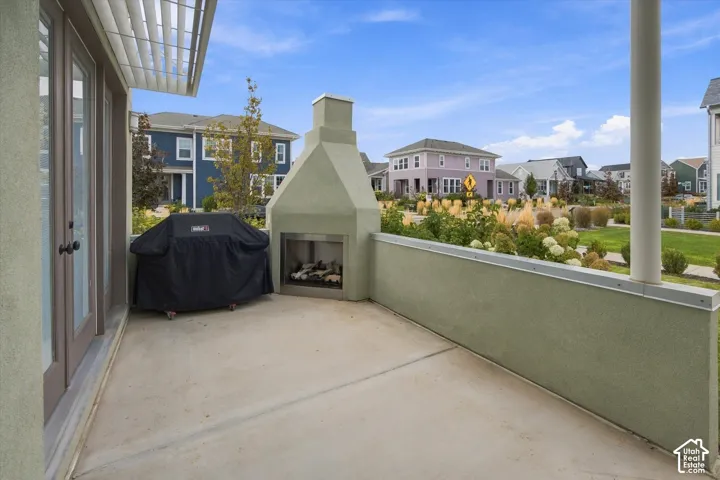 Concrete patio featuring an outdoor fireplace with a stainless steel firebox, stucco exterior, and double glass doors
