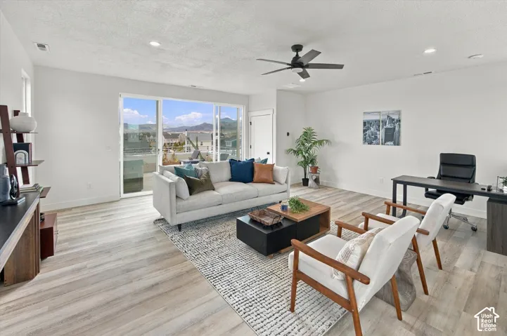 Bright living area featuring wood-finish flooring, a ceiling fan, recessed lighting, and a sliding glass door