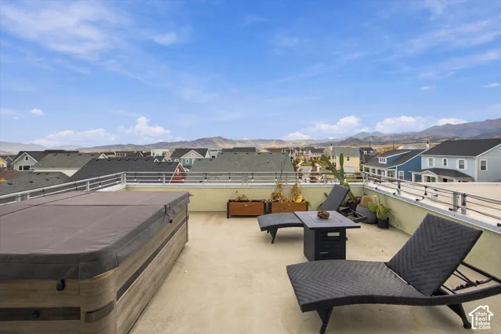 Rooftop deck featuring a built-in hot tub, concrete flooring, and metal railings