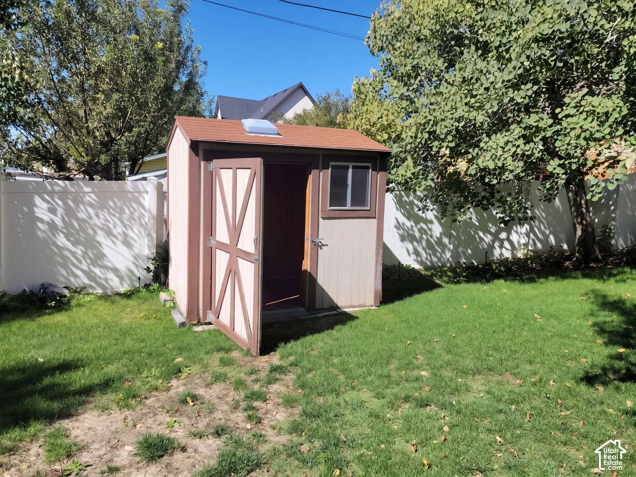 Storage shed featuring a skylight and a side window, situated on a grassy lawn