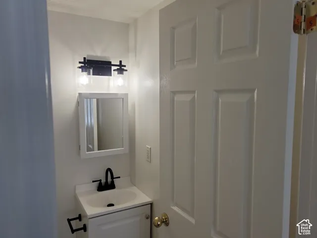White vanity with a single basin sink, matte black faucet, and coordinating wall-mounted light fixture