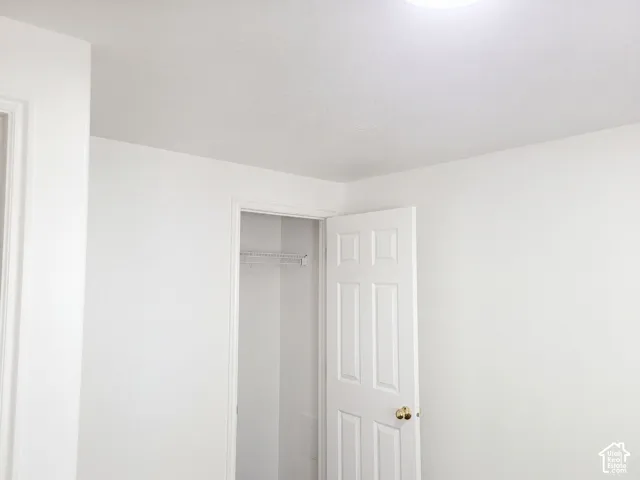White interior walls with a white ceiling, featuring a flush-mount ceiling light and a white paneled door with a brass-finish knob