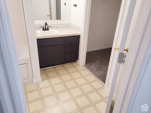Bathroom featuring patterned tile flooring, a dark wood-finish vanity with a light-colored countertop, a rectangular sink, and a matte black faucet