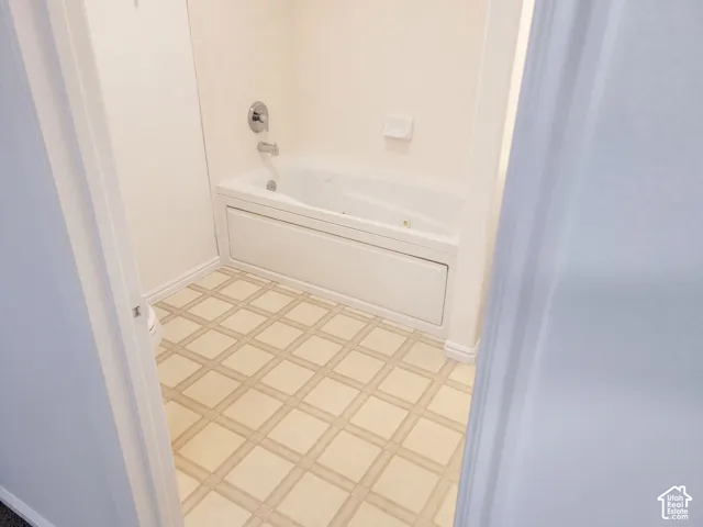 White built-in bathtub with chrome fixtures and patterned floor tile