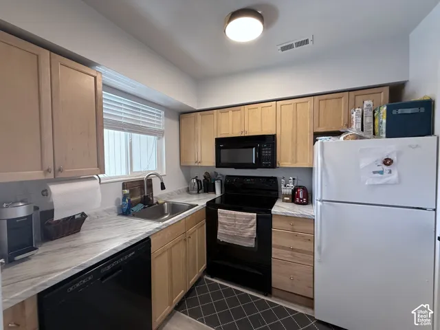 Kitchen featuring wood-finish cabinetry, light-toned countertops, and a stainless steel sink with a gooseneck faucet