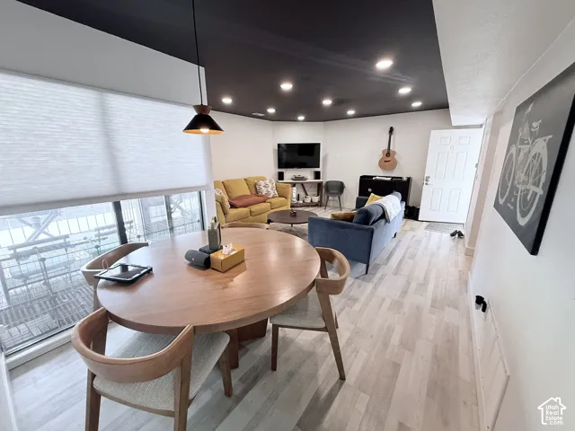 Recessed lighting, wood-finish flooring, white paneled door, large windows, and a modern pendant light fixture