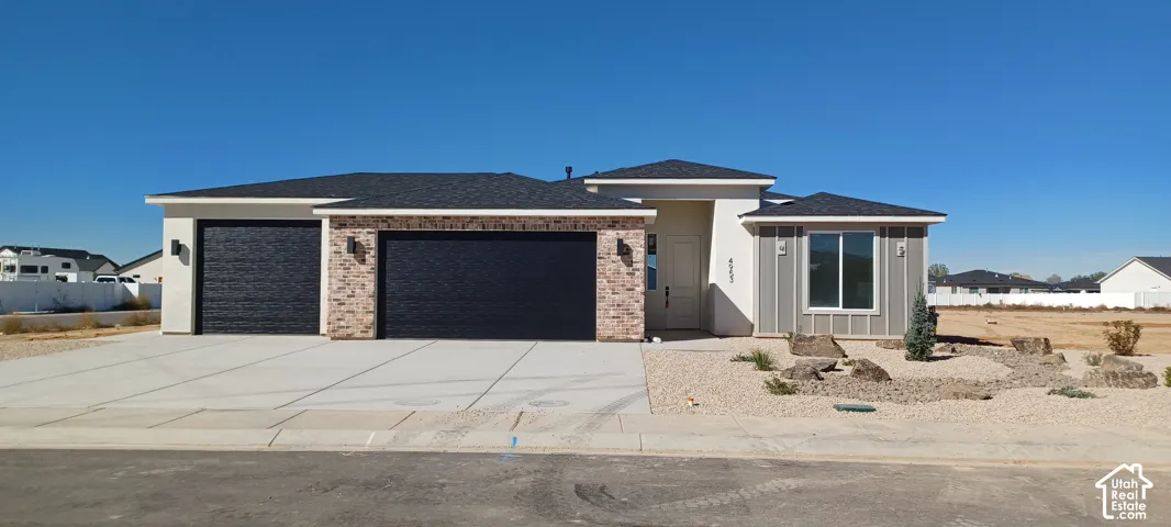 Contemporary exterior with textured garage doors, brick facade accents, and a low-maintenance landscape design