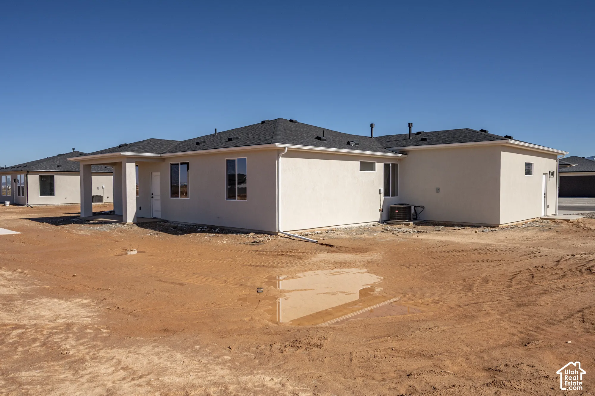 Single-story stucco exterior featuring a dark asphalt shingle roof, integrated covered patio, and dual-pane windows