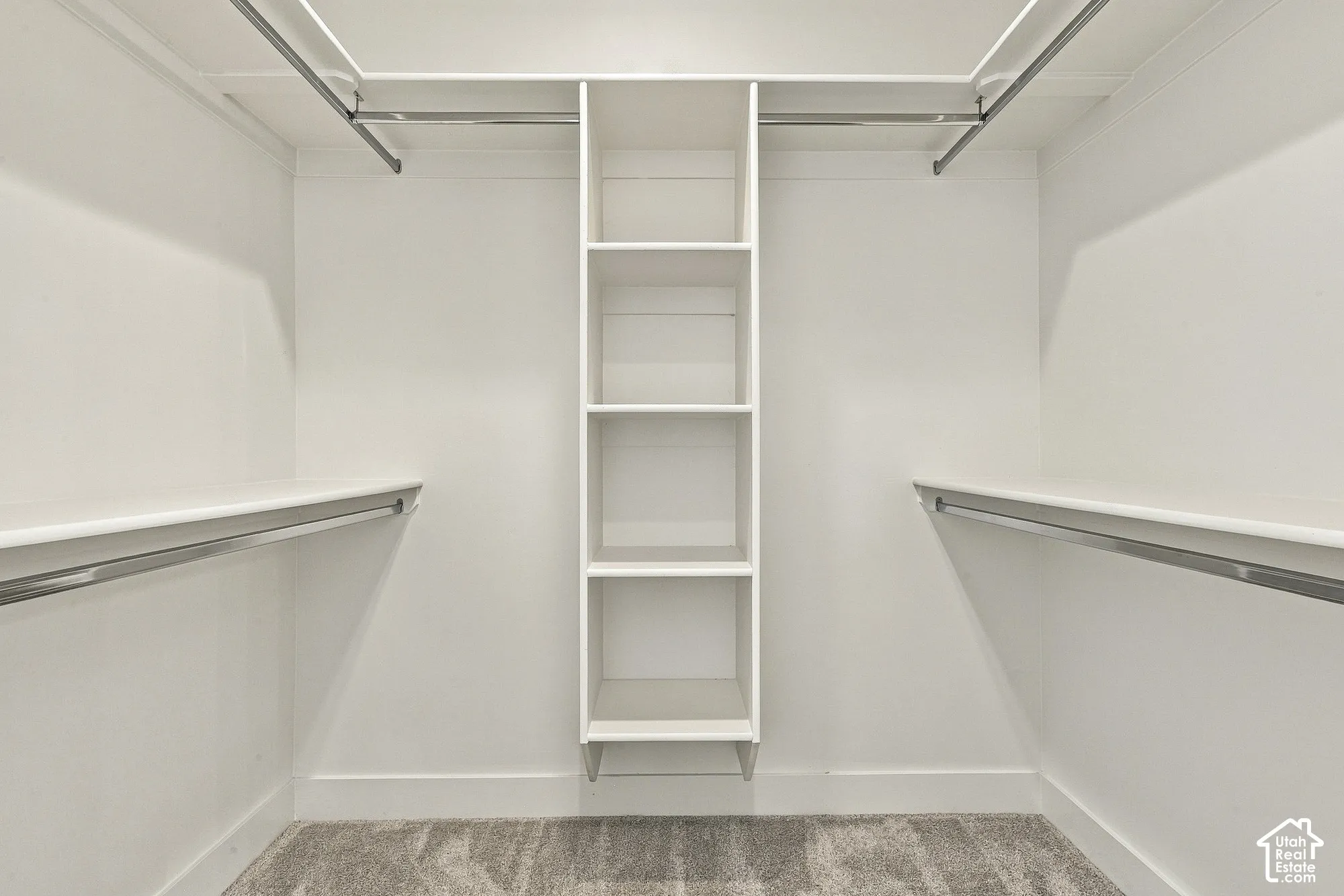 Walk-in closet featuring floor-to-ceiling built-in shelving, dual tiered hanging rods, and neutral carpeting
