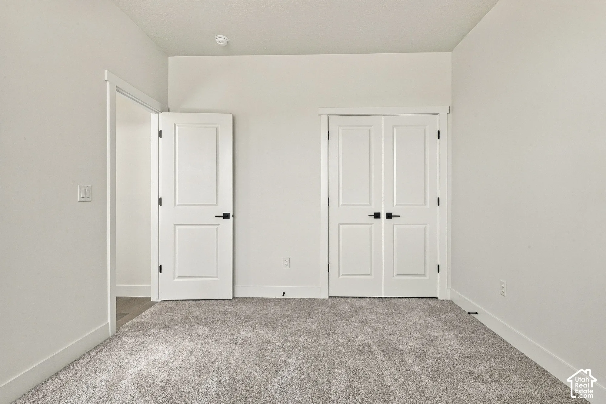 Neutral-toned carpeted flooring, two-panel interior doors, and matte black door hardware
