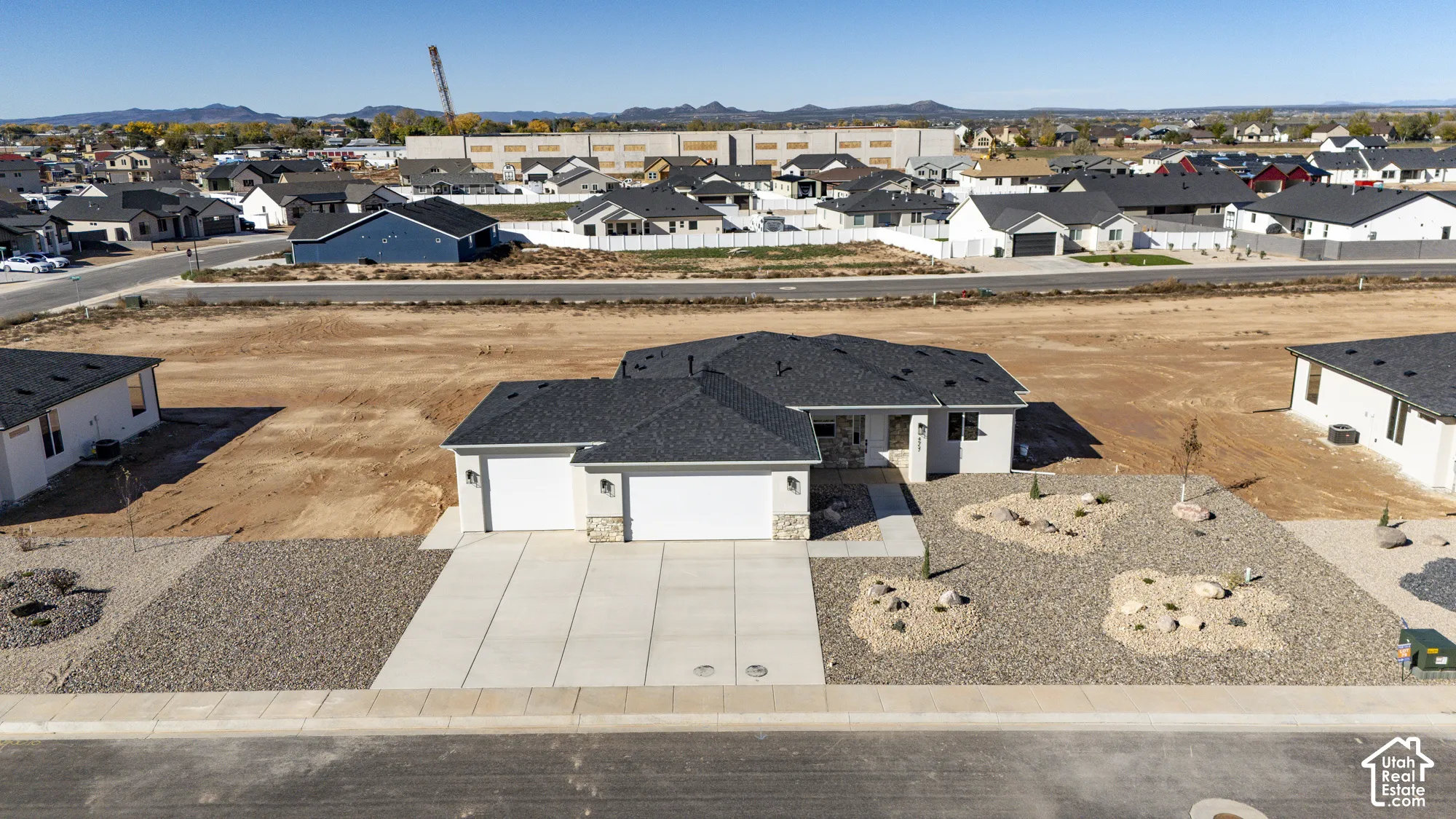 Single-story exterior featuring a hip roof, dual-bay garage, stone masonry accents, and xeriscaped front grounds