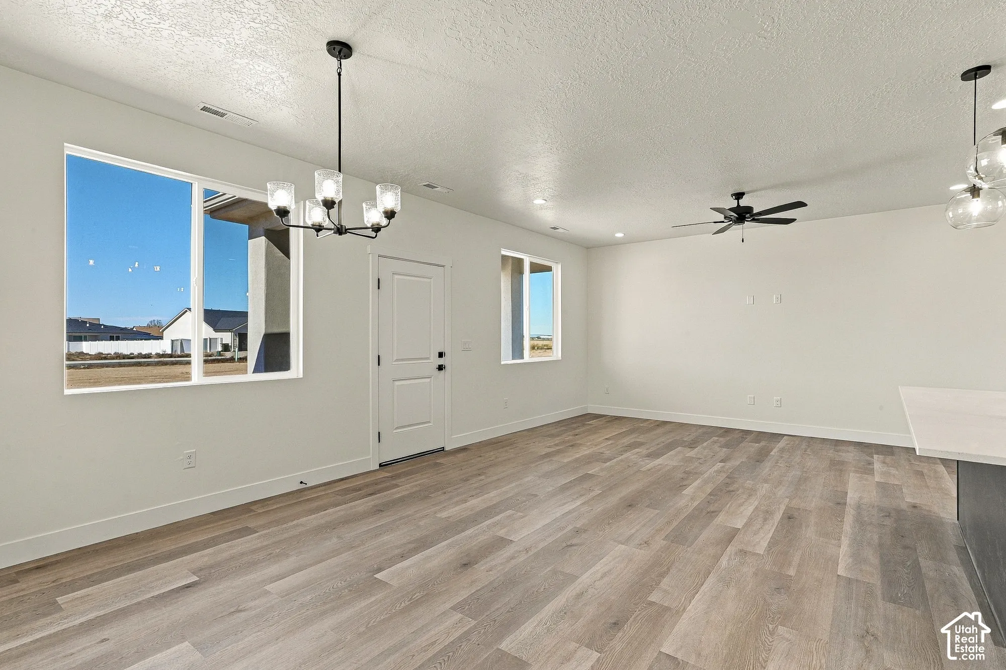 Open-concept interior featuring wood-finish flooring, recessed lighting, a modern multi-bulb chandelier, and a ceiling fan