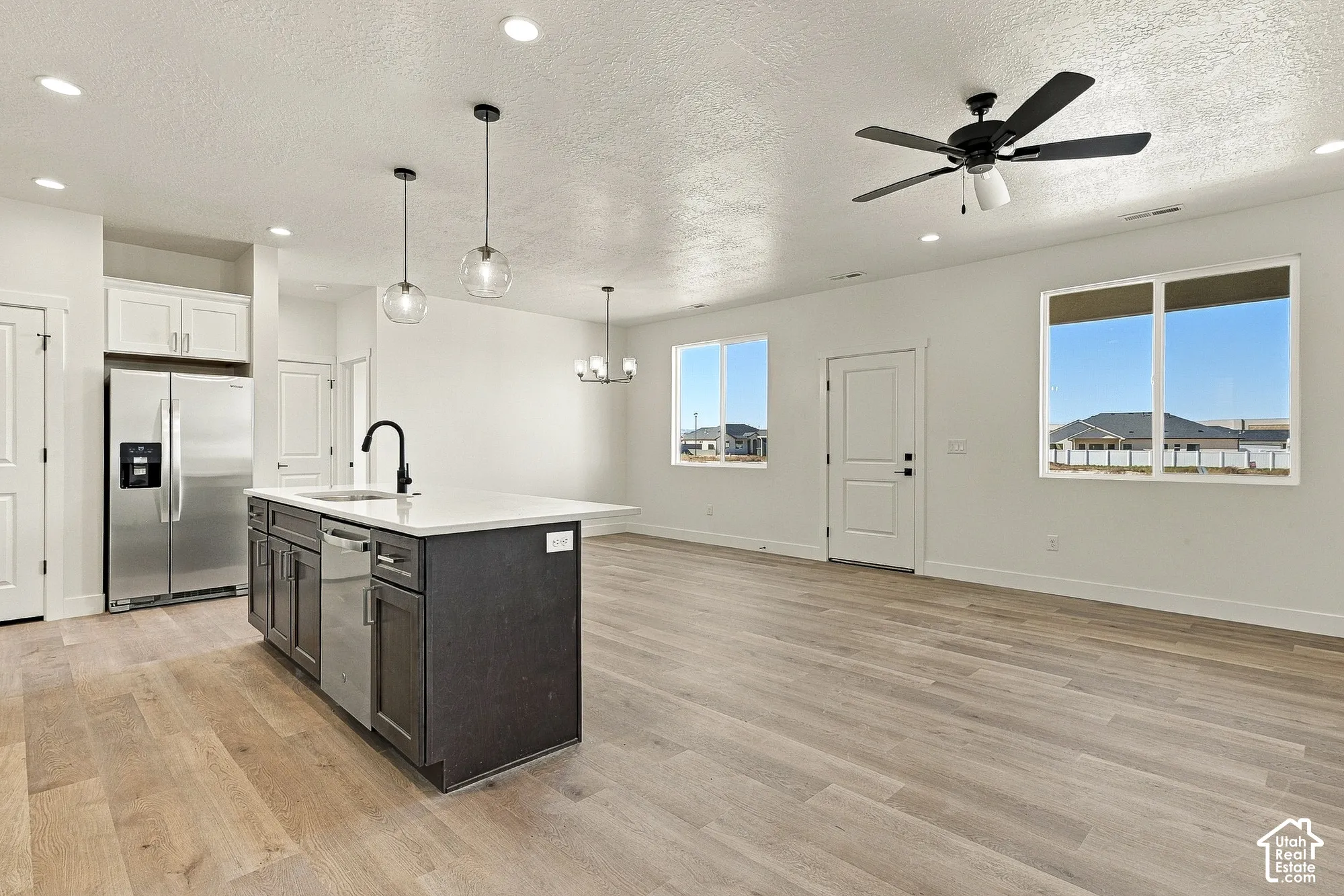 Kitchen featuring a center island with a stone countertop, recessed lighting, glass pendant fixtures, stainless steel appliances, and wood-finish flooring