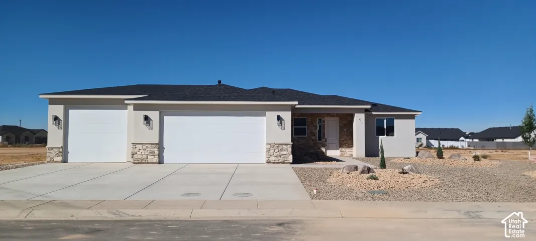Attached two-car garage with individual doors, stucco exterior with stone accents, dark shingle roof, and a gravel front yard with minimal landscaping