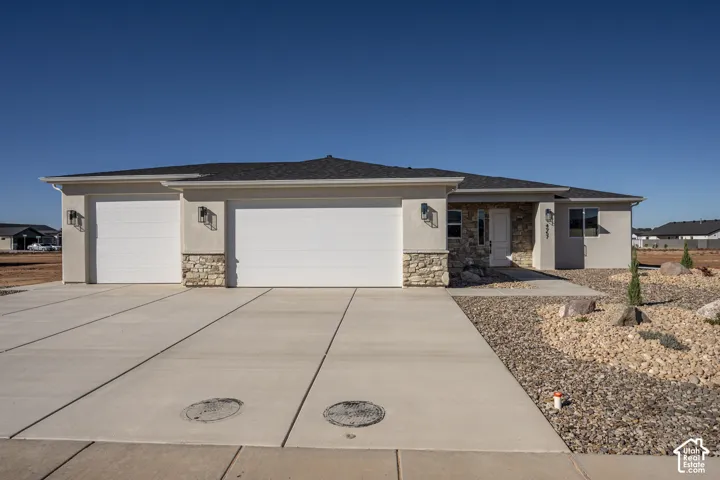 Single-level exterior featuring stucco siding, stone veneer accents, a three-car garage, and concrete driveway