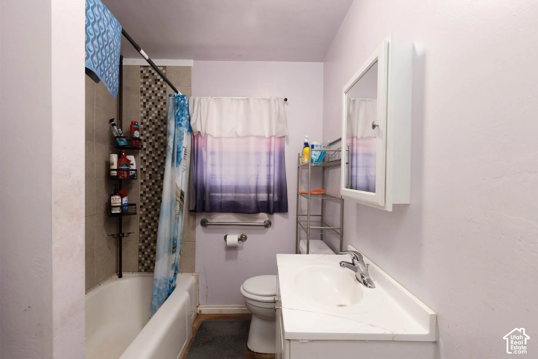 Bathroom featuring a built-in tub with tile surround, a wall-mounted medicine cabinet, a vanity with an integrated sink, and a commode