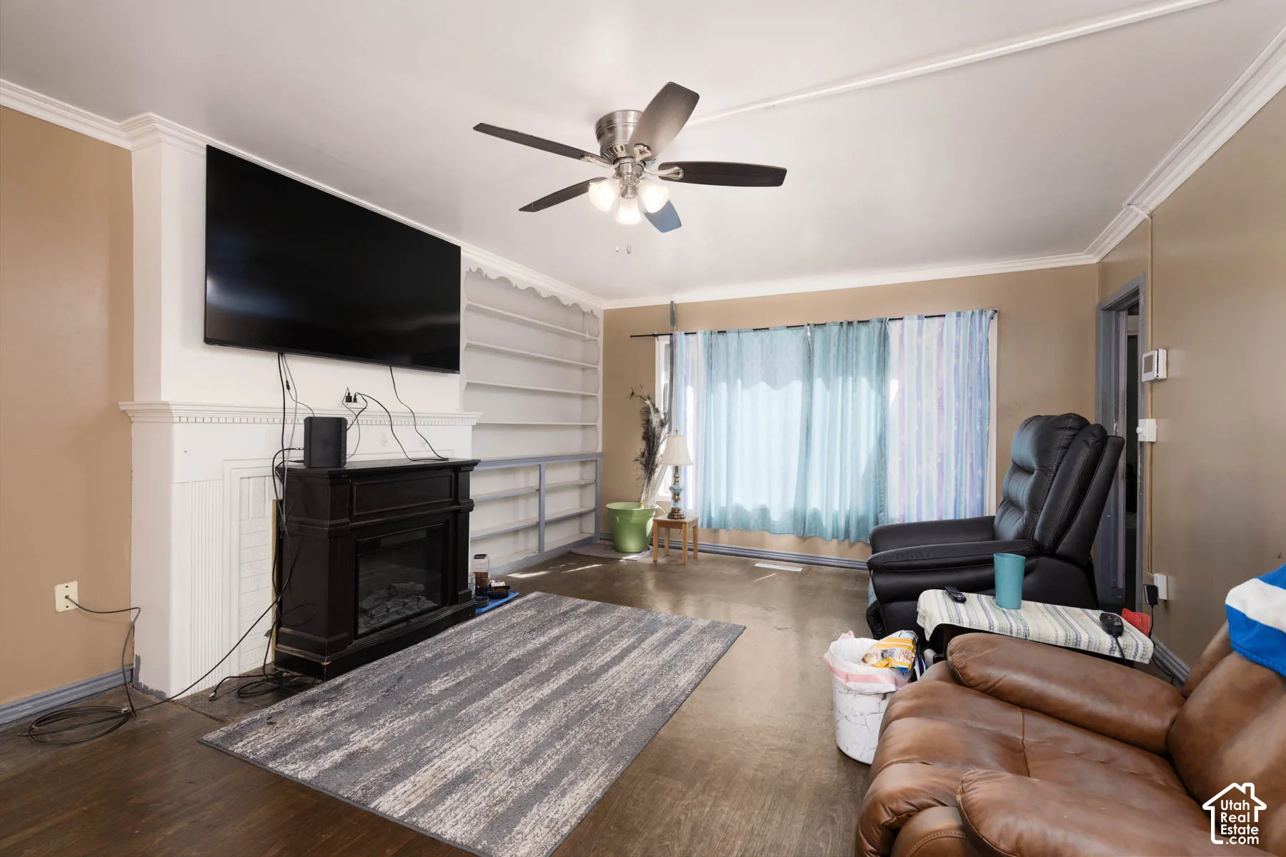 Hardwood-style flooring, white crown molding, built-in shelving, and a decorative fireplace with a mantel