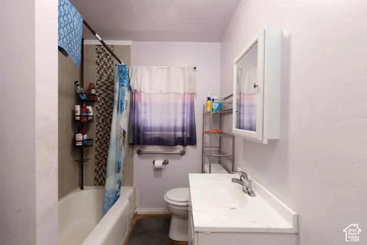 Bathroom featuring a built-in tub with tile surround, a wall-mounted medicine cabinet, a vanity with an integrated sink, and a commode
