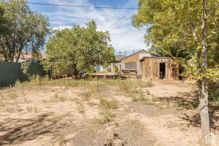 Expansive rear yard with mature trees and a wooden storage shed