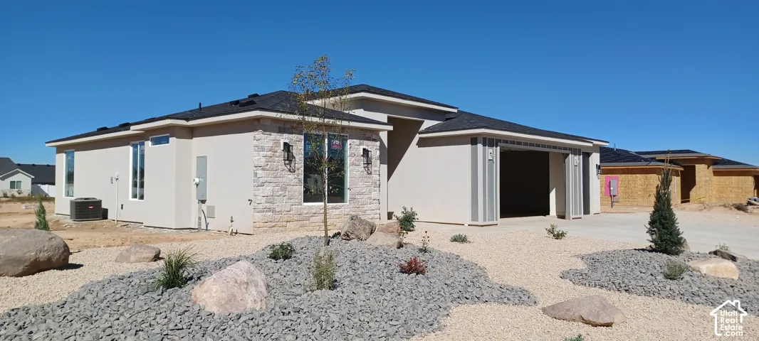 Modern exterior with stucco finish and stone accents, featuring a multi-car garage and xeriscape landscaping