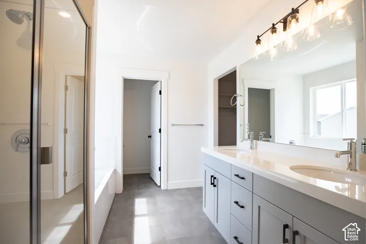 Primary bath with dual sinks, painted wood cabinets, quartz slab countertops, soaker tub and walk-in shower.