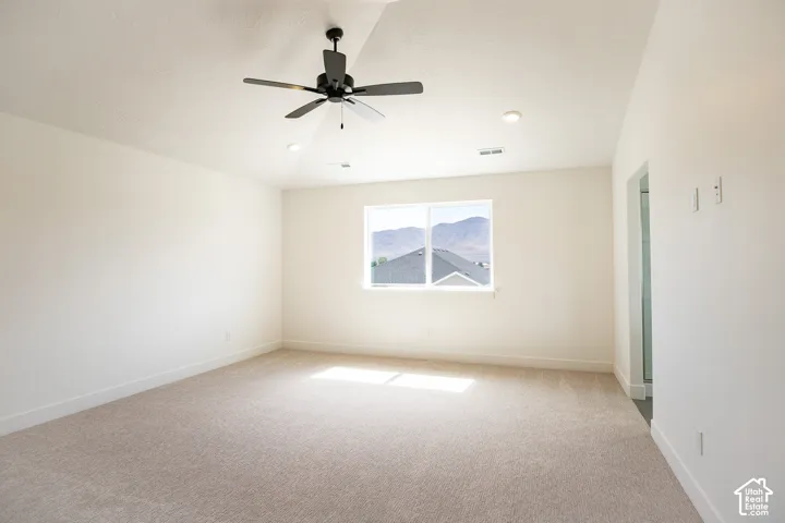 Primary bedroom with vaulted ceiling, built-in shelves and ceiling fan.