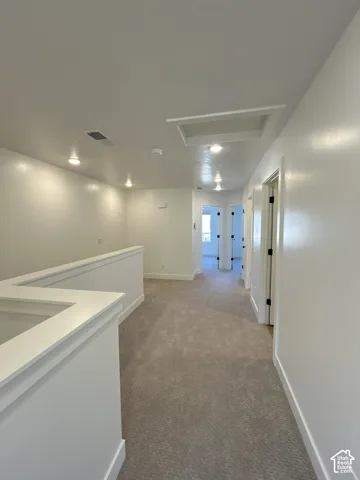 Carpeted hallway featuring white walls, recessed lighting, and white trim