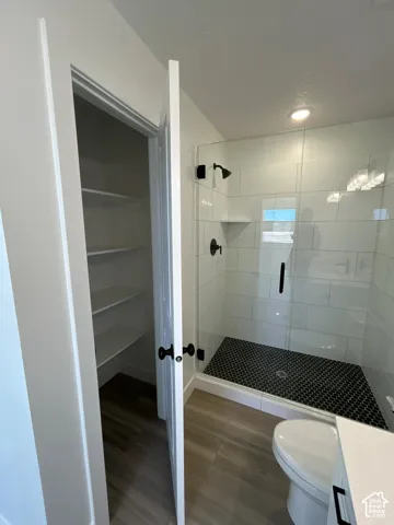 Walk-in shower with black hexagonal tile flooring and subway tile surround, clear glass enclosure, and matte black fixtures