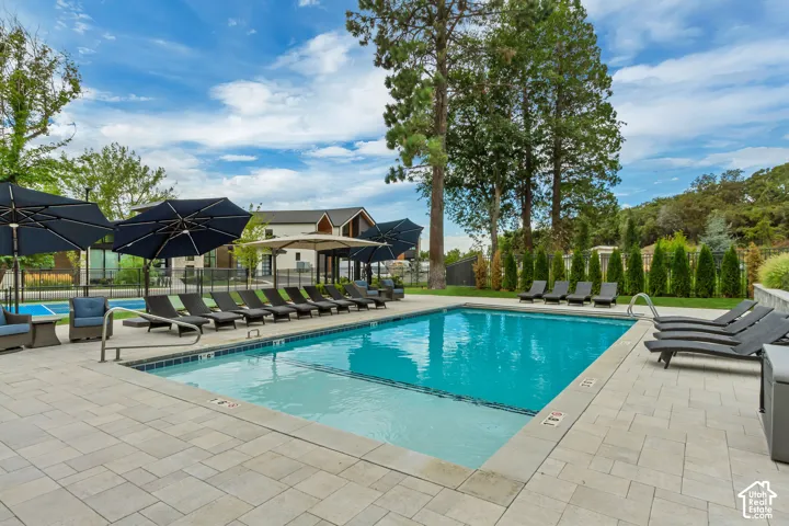 Outdoor swimming pool with integrated steps, surrounding paver patio, and adjacent tennis court