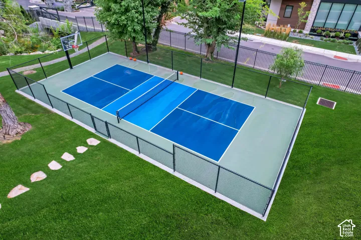 Multi-sport court featuring a basketball hoop and net, enclosed by a black perimeter fence
