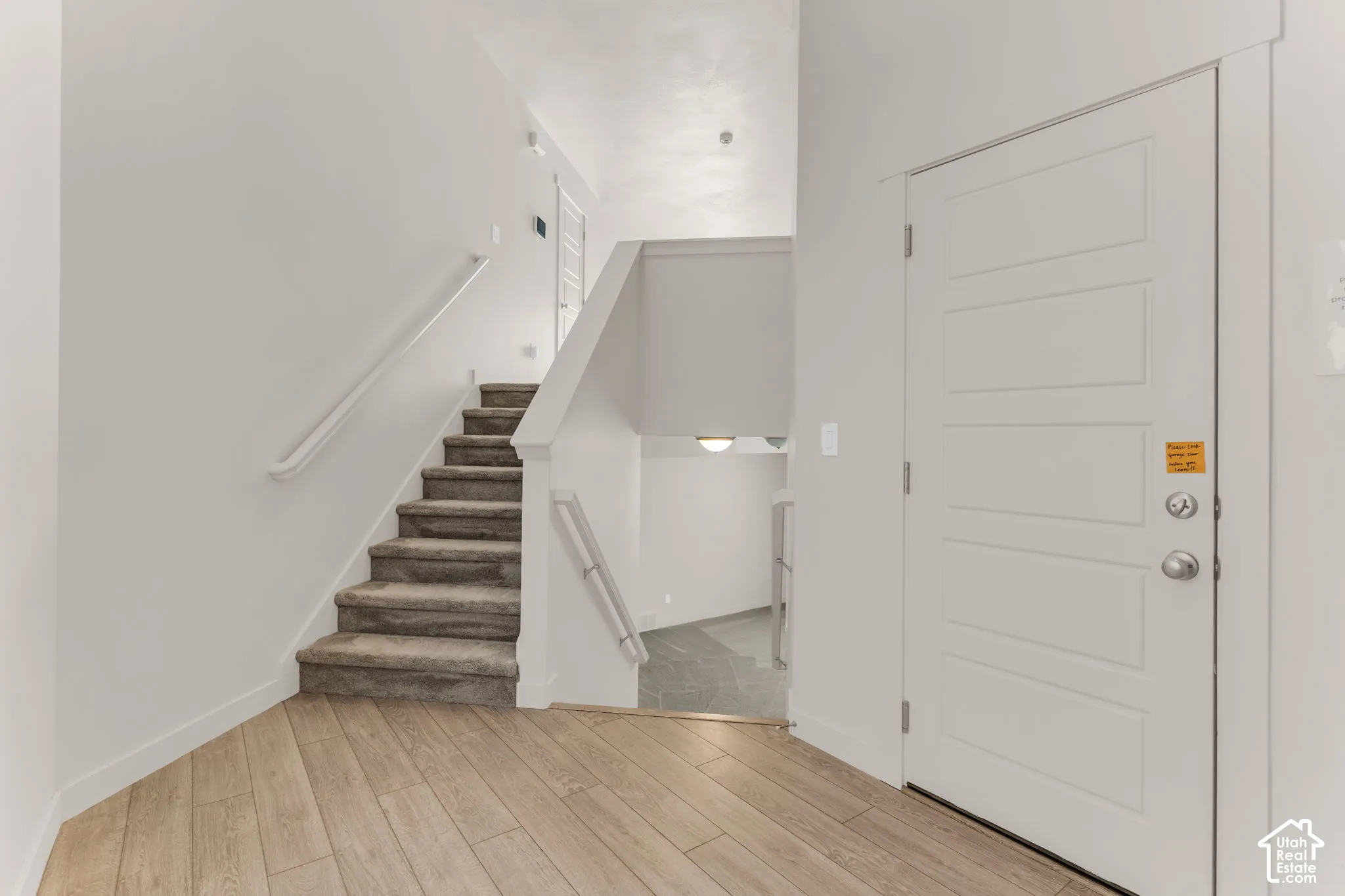 Wood-finish flooring with a multi-level staircase featuring carpeted treads and white handrails