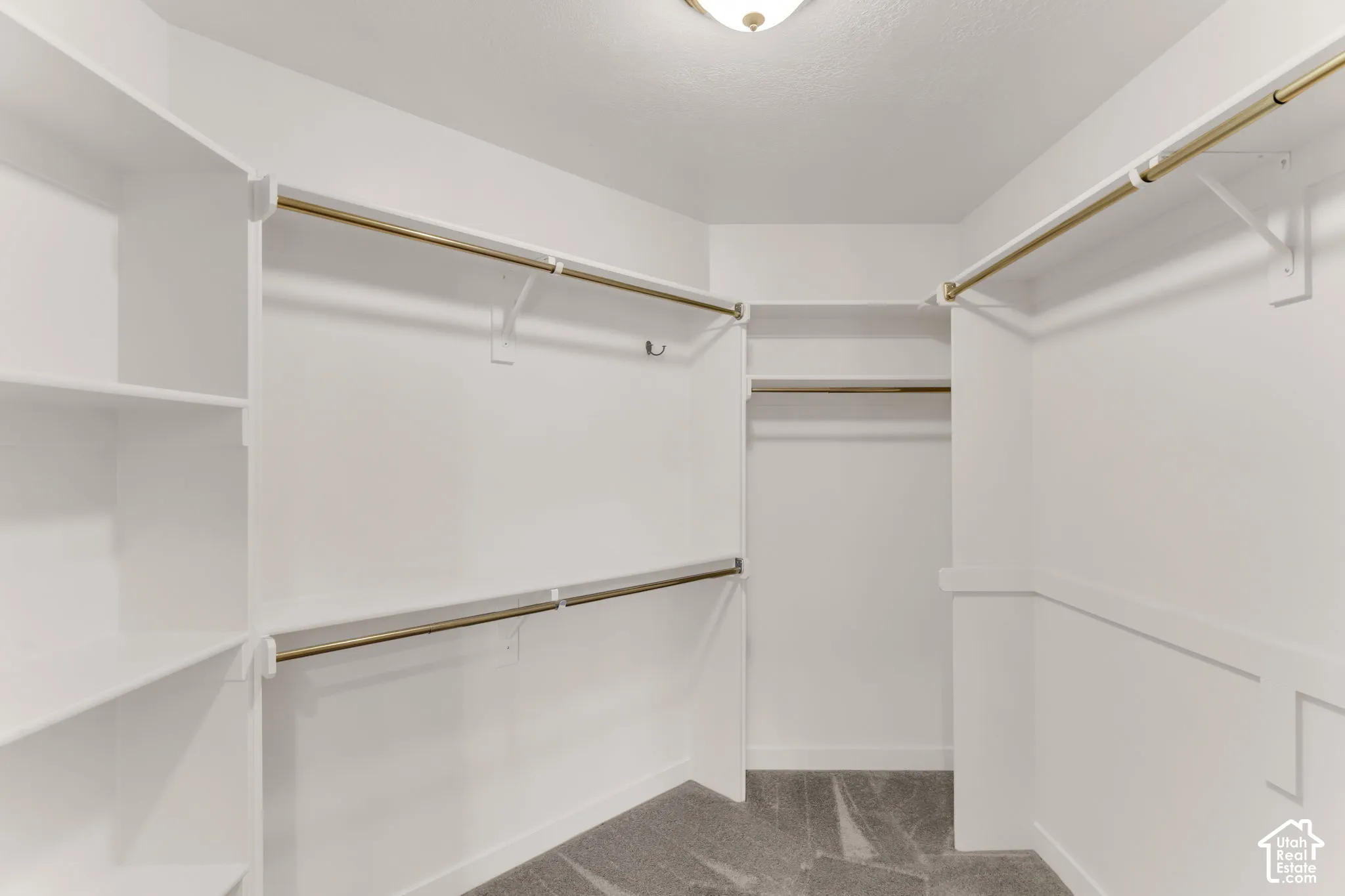 Owner's Suite - Walk-in Closet - White painted built-in shelving, multiple brass-finish hanging rods, and grey patterned carpet
