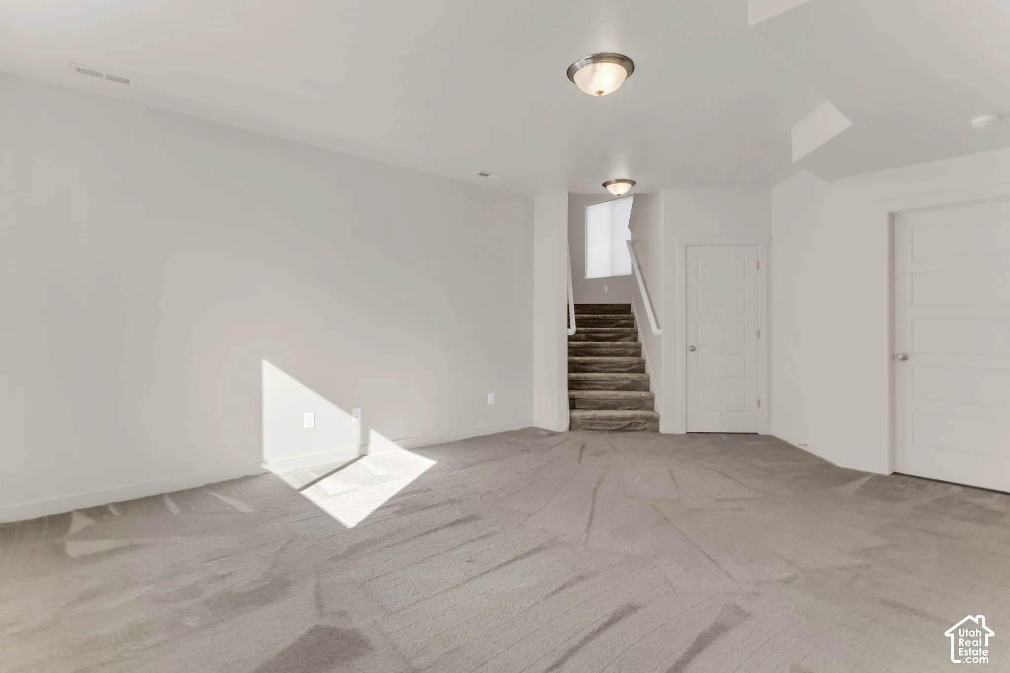 Spacious room featuring neutral carpeting and light-colored walls