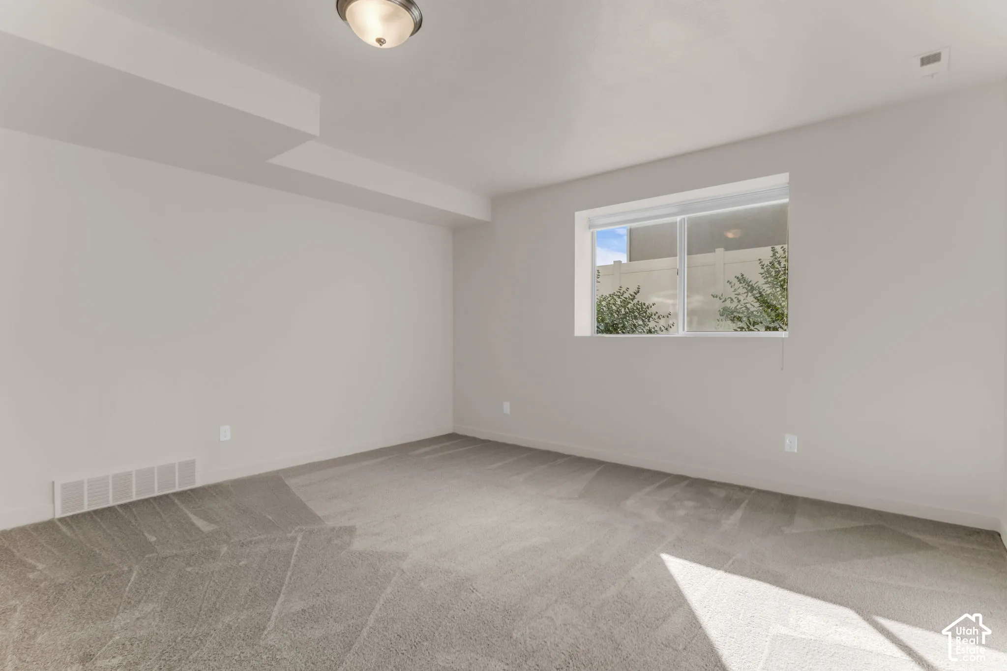 Recessed lighting, neutral wall tones, window with white trim, and light gray carpeting