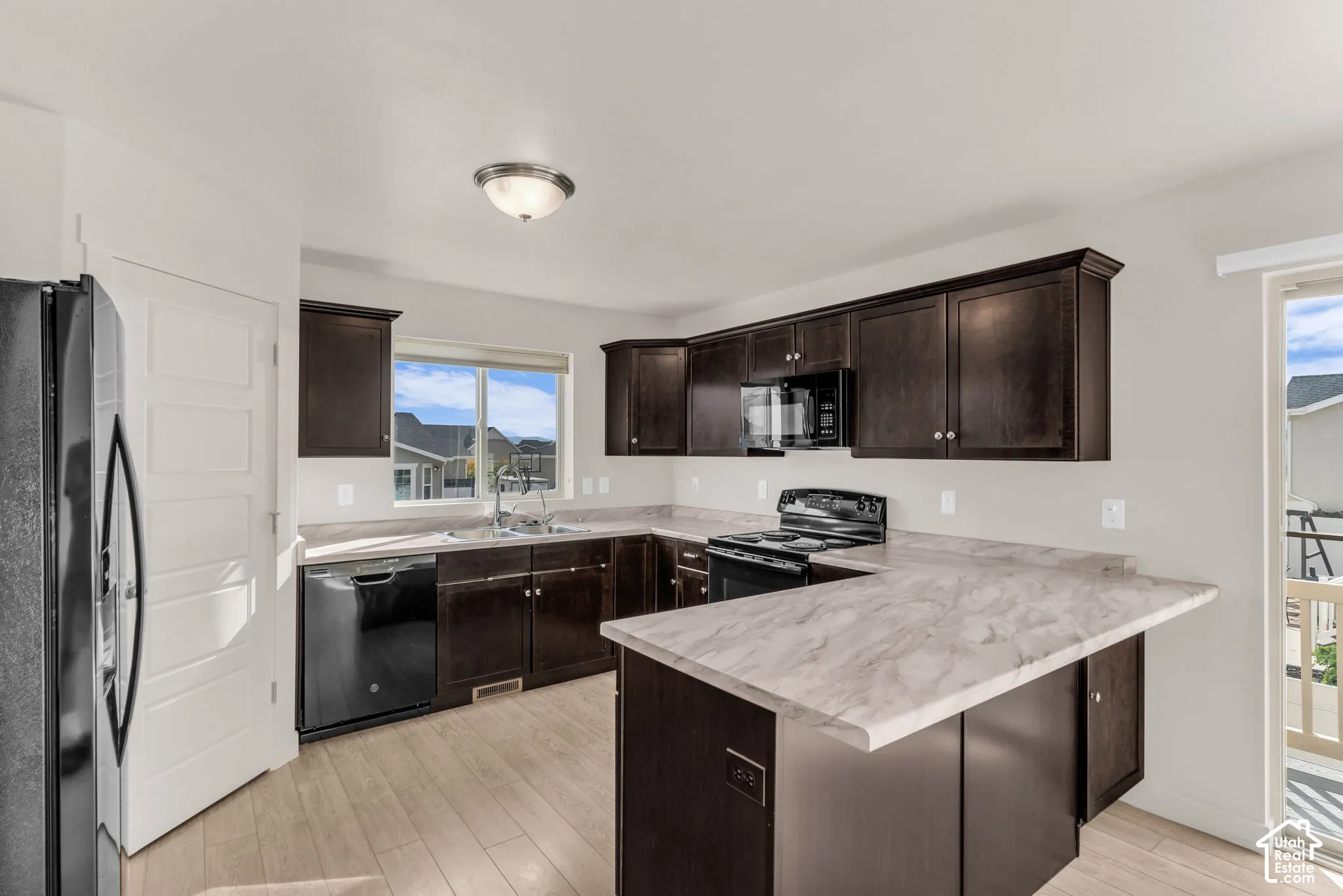 Kitchen featuring dark wood-finish cabinetry, light wood-finish flooring, and light-toned countertops