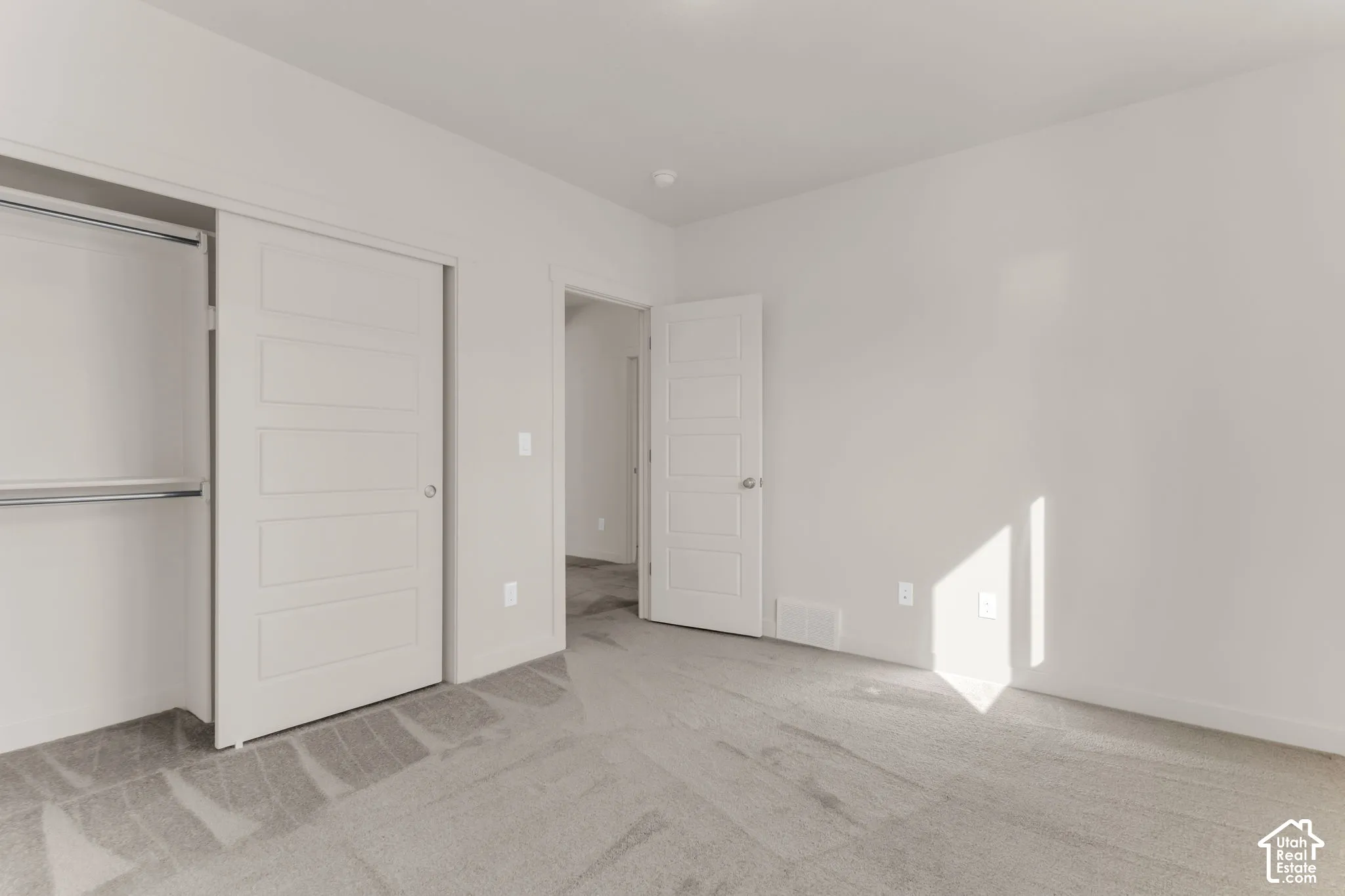 Light gray wall-to-wall carpeting, white interior walls, and a white interior door