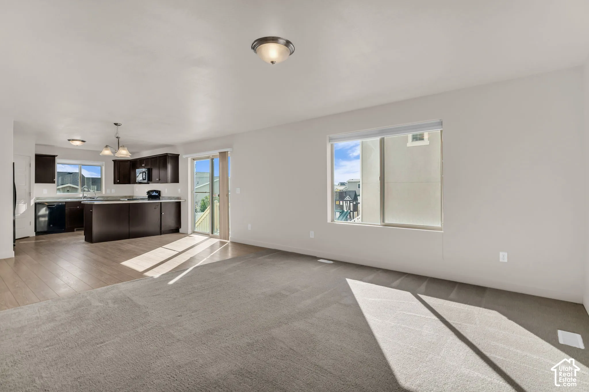 Open-concept living space featuring wood-finish flooring, dark wood cabinetry, and a sliding glass door