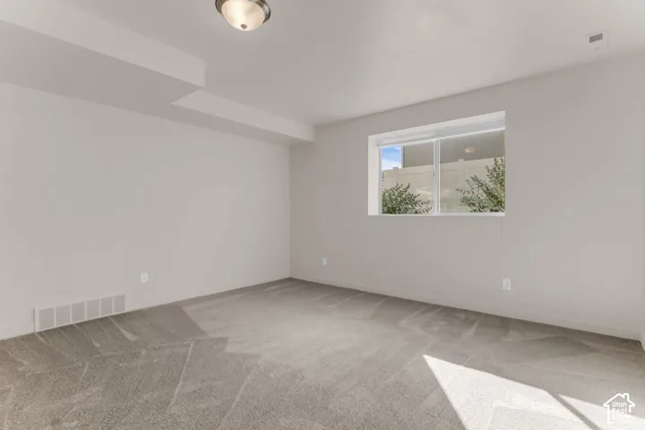 Recessed lighting, neutral wall tones, window with white trim, and light gray carpeting