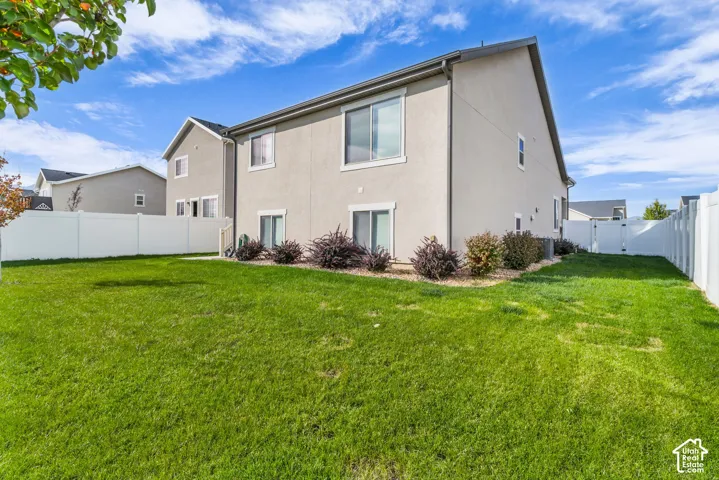 Expansive green lawn, white vinyl fencing, mature perimeter plantings, ground-level sliding glass doors, and upper-level windows