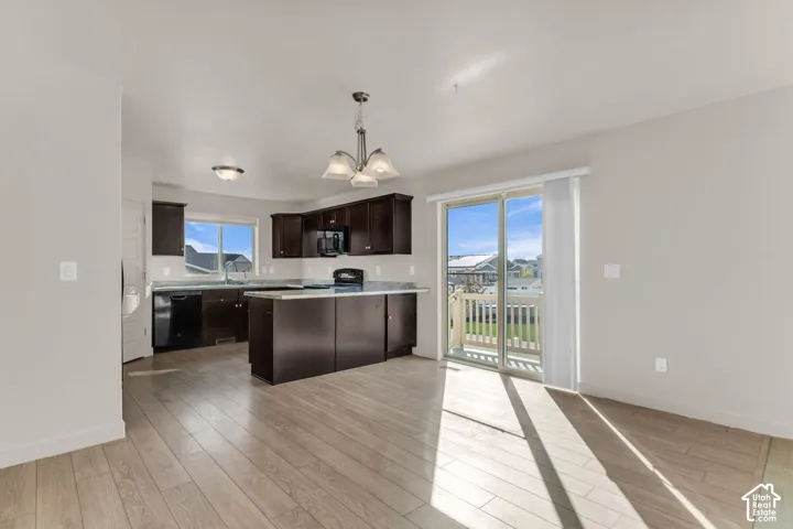 Open-concept kitchen and dining area featuring wood-finish flooring, dark wood cabinetry, a kitchen island with seating, and a sliding glass door to a deck