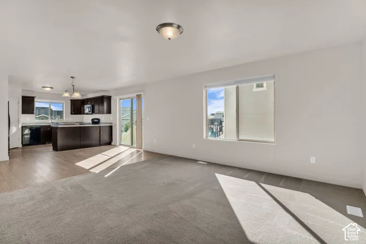 Open-concept living space featuring wood-finish flooring, dark wood cabinetry, and a sliding glass door